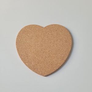 May include: A heart-shaped cork coaster in a light brown colour.