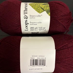 May include: Two skeins of Loops & Threads Impeccable acrylic yarn in burgundy. Each skein has 285 yards and weighs 4.5 oz. The label includes the color name, product details, and a barcode.