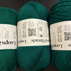 May include: Three skeins of dark emerald green acrylic yarn. Each skein has a white label with the brand name "Loops & Threads" and the word "Impeccable". The label also includes the yarn weight, 4.5 oz, and the length, 285 yards.