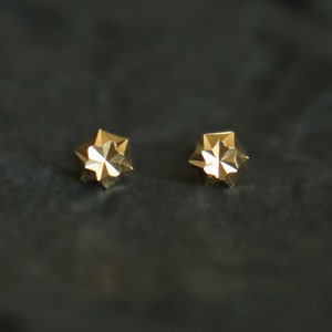 Puede incluir: Un par de pendientes de estrella de oro. Los pendientes son peque&ntilde;os y delicados, y tienen un dise&ntilde;o geom&eacute;trico.