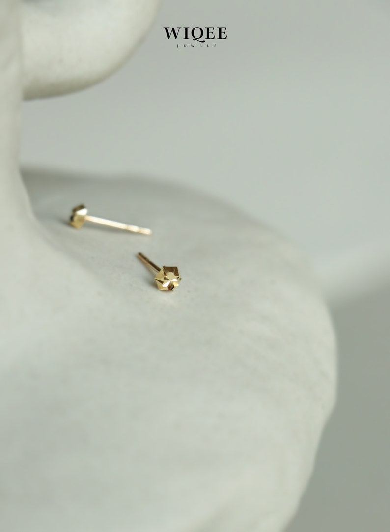 Puede incluir: Un par de pendientes de bot&oacute;n geom&eacute;tricos de oro. Los pendientes son peque&ntilde;os y tienen un dise&ntilde;o facetado.