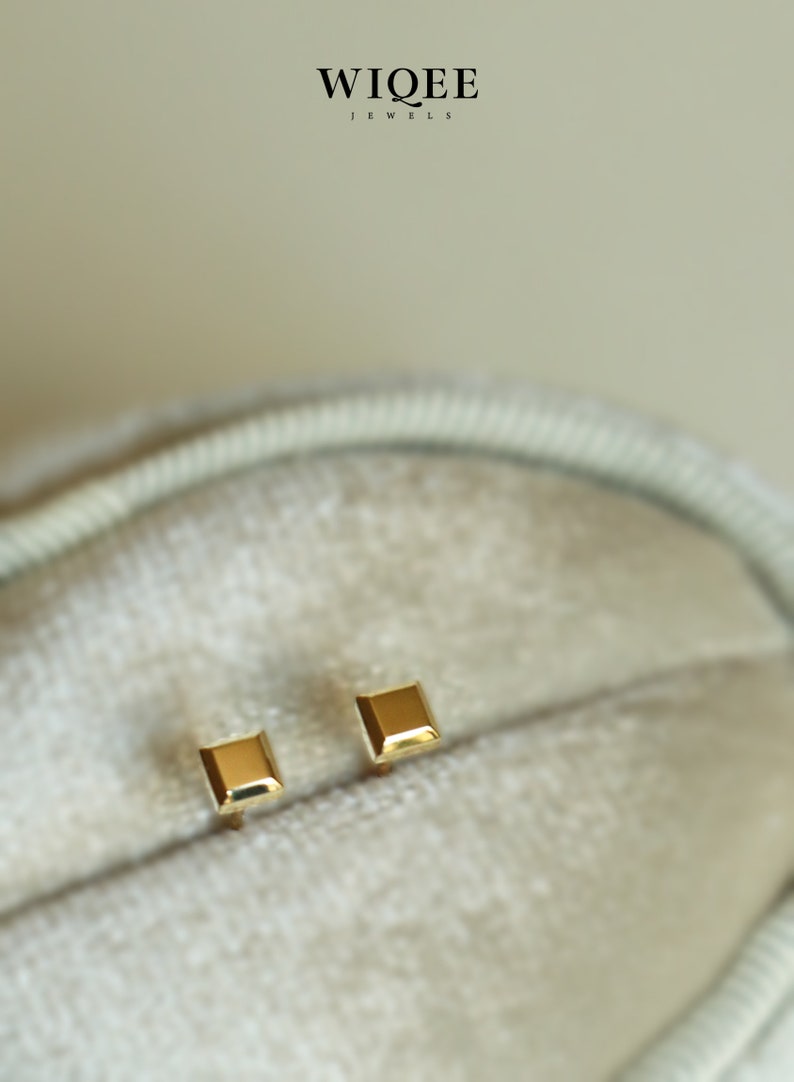 May include: A pair of gold square stud earrings. The earrings are small and simple, and they are perfect for everyday wear.