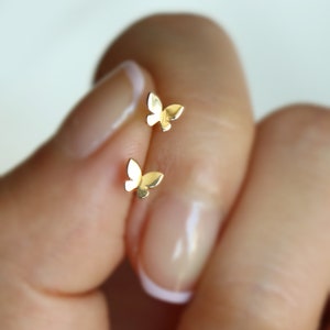 Puede incluir: Un par de pendientes de mariposa de oro. Los pendientes son pequeños y delicados, y son perfectos para el uso diario.
