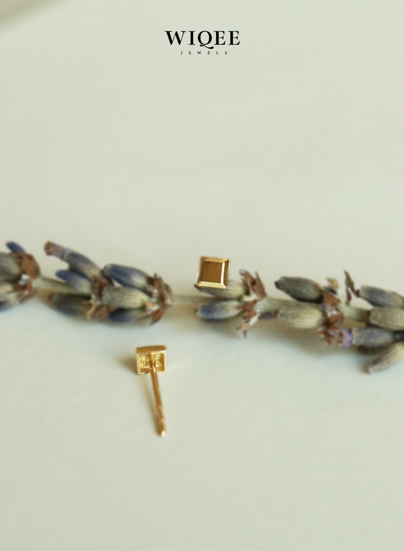 May include: A pair of gold square stud earrings. The earrings are small and delicate, and they are perfect for everyday wear.