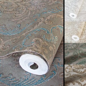 May include: A roll of wallpaper featuring a dark brown background with a raised, textured damask pattern in metallic bronze and teal blue. The design includes intricate scrolling leaves and floral motifs, shown in multiple colour variations.