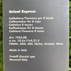 Puede incluir: Una caja de producto con el texto "Orient Express" y varias traducciones de "Cafetera para 8 tazas". La caja tambi&eacute;n enumera las dimensiones como 10,5x17x21,5 cm y "Made in Italy".