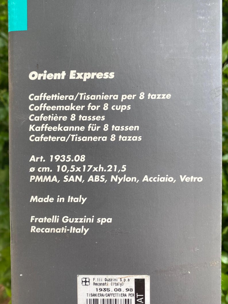 Puede incluir: Una caja de producto con el texto "Orient Express" y varias traducciones de "Cafetera para 8 tazas". La caja tambi&eacute;n enumera las dimensiones como 10,5x17x21,5 cm y "Made in Italy".