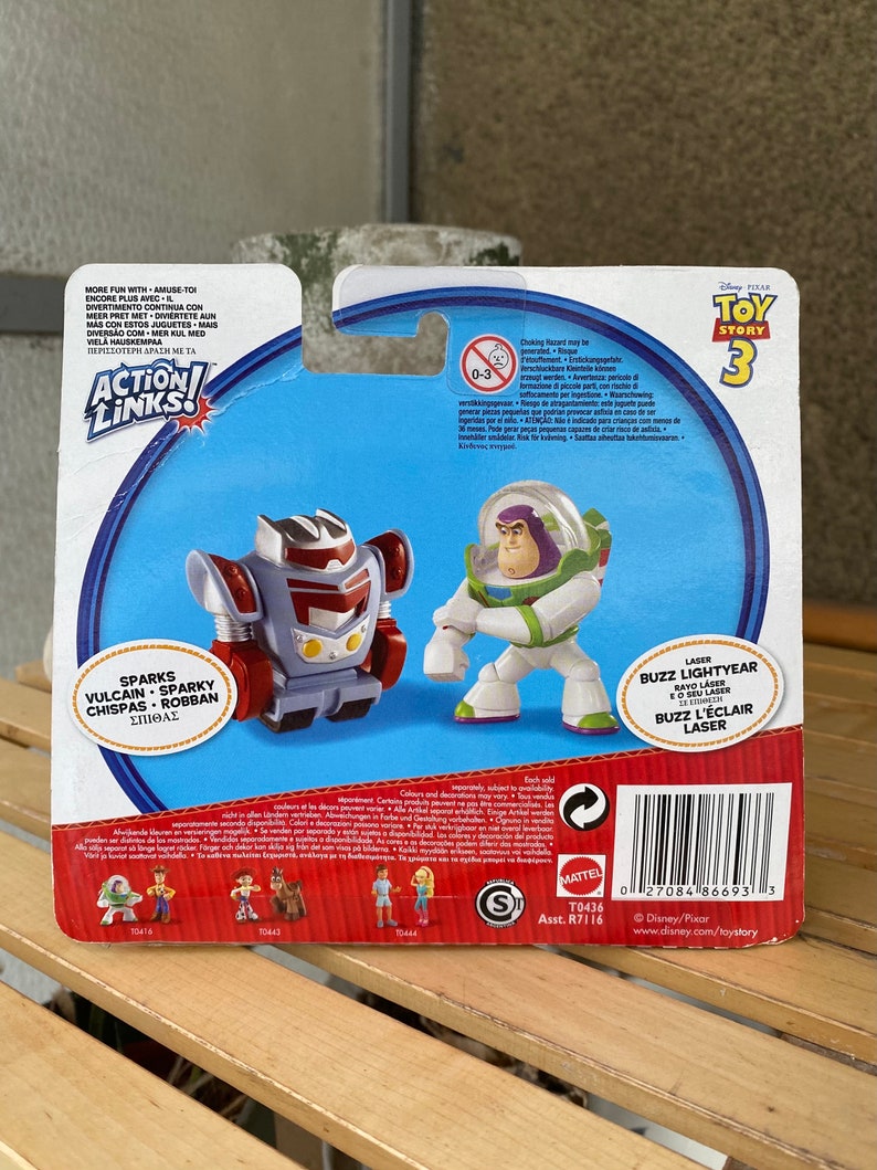 May include: Toy Story 3 Action Links figure set featuring Buzz Lightyear and Sparks Vulcan. Buzz Lightyear is wearing his classic space ranger suit and holding his laser. Sparks Vulcan is a red, white, and blue robot with a large head and a small body. The packaging features the Toy Story 3 logo and the Action Links logo.