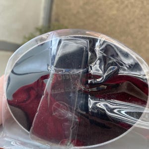 May include: A black and silver round object with a red and black background. The object is wrapped in clear plastic and has the text "Made in China" printed on it.
