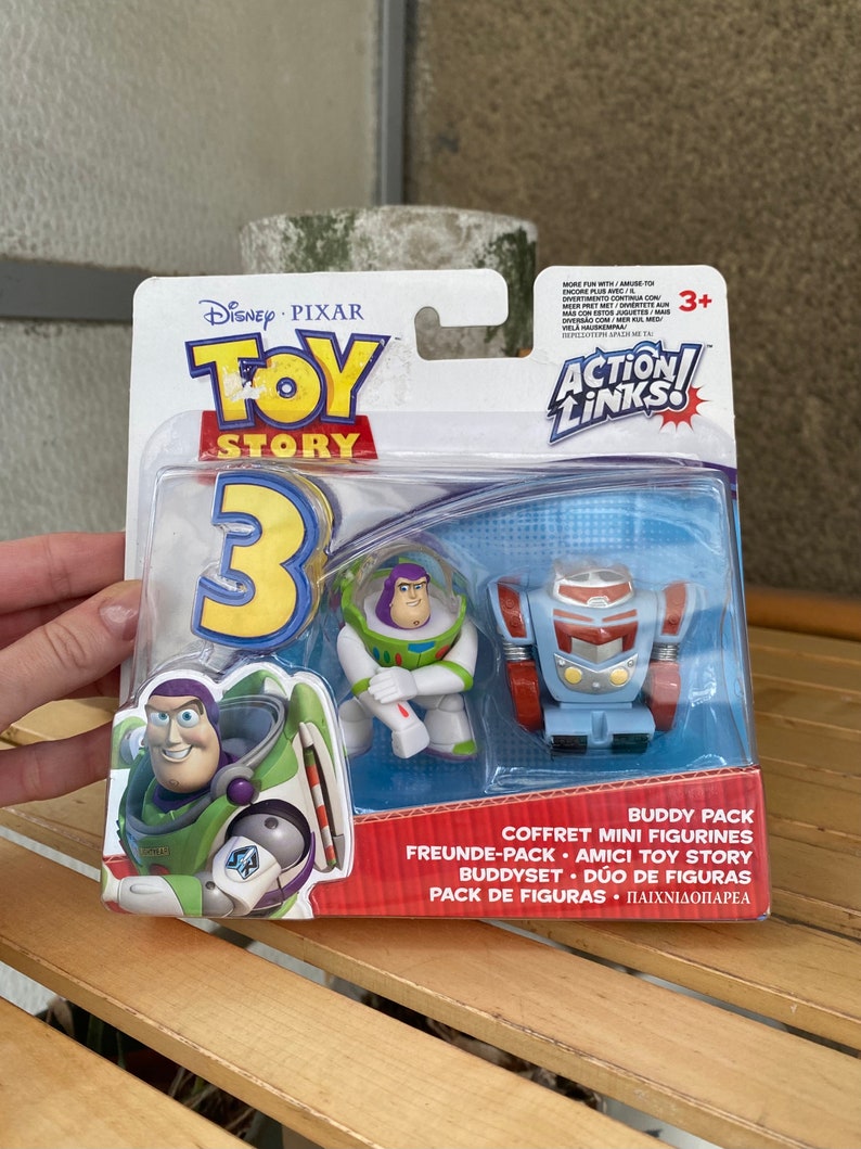 May include: Toy Story 3 Action Links Buddy Pack featuring Buzz Lightyear and a robot character. The packaging is blue and white with the Toy Story 3 logo and the words "Action Links" in a red circle.