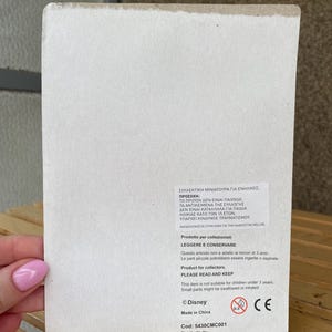 May include: A white cardboard box with a warning label in Greek and English. The label states that the product is a collectible miniature for adults only and is not suitable for children under 3 years old. The box also includes the Disney logo, a CE mark, and the product code: 5430CMC001.