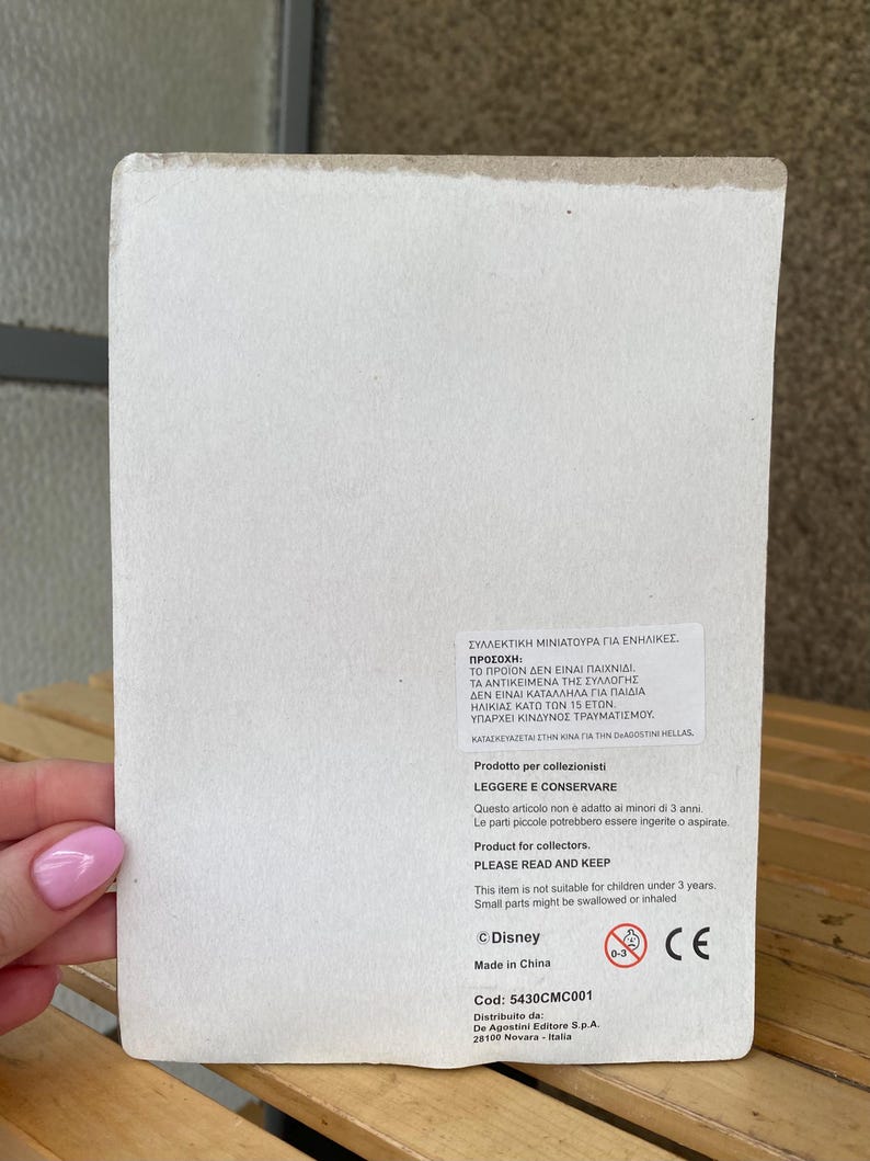 May include: A white cardboard box with a warning label in Greek and English. The label states that the product is a collectible miniature for adults only and is not suitable for children under 3 years old. The box also includes the Disney logo, a CE mark, and the product code: 5430CMC001.