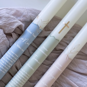 Könnte beinhalten: Drei weiße Kerzen mit goldenen Akzenten und Text. Die Kerzen sind mit einer Taube, einem Kreuz und einem Zweig verziert. Der Text auf den Kerzen lautet "Meine Taufe", "Meine Kommunion" und "Meine Kommunion". Die Daten auf den Kerzen sind der 23. März 2013, der 4. Mai 2025 und der 22. Mai 2025.