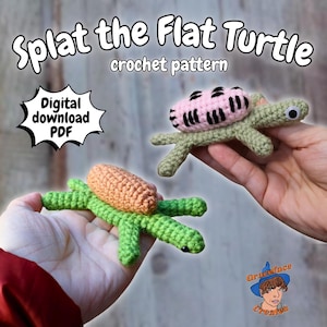 May include: Two crocheted turtles, one with a pink shell and the other with an orange shell, are held in hands. The turtles are green with googly eyes. Text reads "Splat the Flat Turtle crochet pattern" and "Digital download PDF".