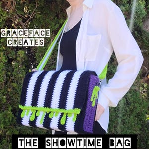 Op de afbeelding: Een zwart-wit gestreepte gehaakte tas met een groene en paarse bies. De tas heeft een limoengroene schouderband en de tekst "The Showtime Bag" is onder de tas gedrukt.
