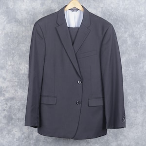 May include: A dark gray suit jacket with a single button closure. The jacket has a notched lapel and two flap pockets.