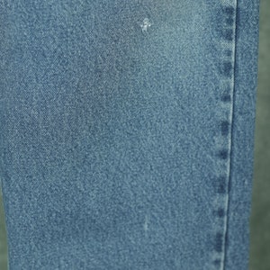 Peut inclure: Gros plan sur un tissu en jean bleu avec une texture subtile. Le tissu a une couture qui descend sur le c&ocirc;t&eacute; droit.