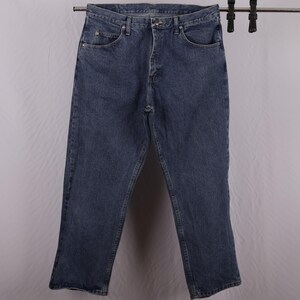 May include: Blue denim jeans with a classic five-pocket design. The jeans are hanging on a metal rack. The jeans have a straight leg cut and a button and zip closure. The jeans are made of a durable denim material.