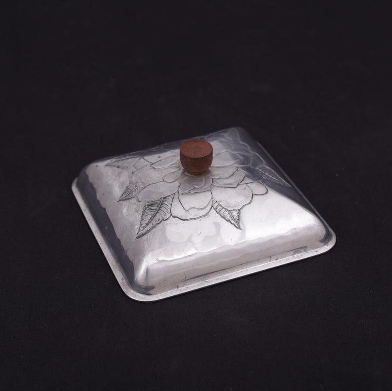 May include: A silver square box with a floral design and a wooden knob on the lid.