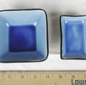 May include: Two blue and black ceramic dishes. The larger dish is square and the smaller dish is rectangular.