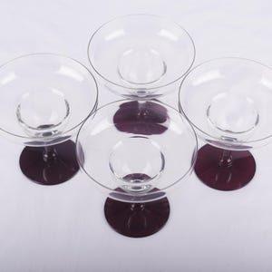 May include: Four clear glass cocktail glasses with burgundy colored stems and bases.