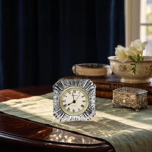 May include: A square crystal clock with a faceted, starburst-like border and a circular face. The clock face is off-white with black Roman numerals, black hands, and the text Shannon Quartz printed in the center. The crystal reflects light.