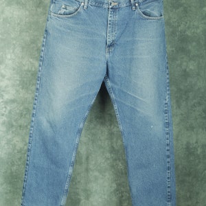 Peut inclure: Un jean en denim bleu clair avec une coupe droite classique. Le jean a une braguette &agrave; boutons et cinq poches.
