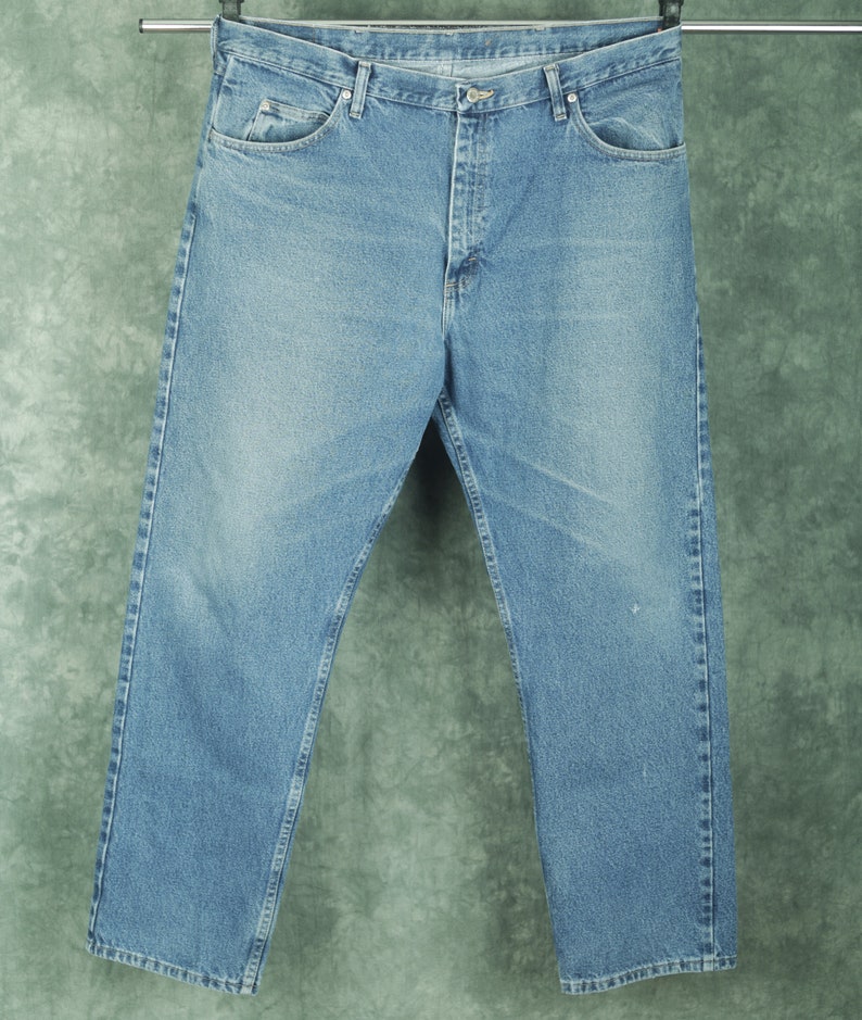 Peut inclure: Un jean en denim bleu clair avec une coupe droite classique. Le jean a une braguette &agrave; boutons et cinq poches.
