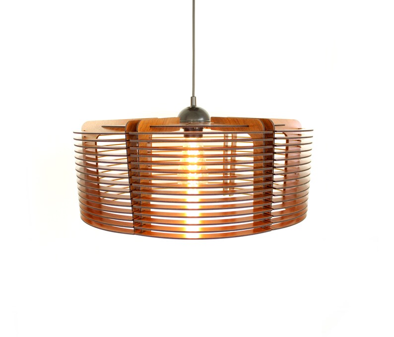 Puede incluir: Una moderna l&aacute;mpara colgante con un brillo c&aacute;lido y acogedor. La l&aacute;mpara presenta una pantalla circular de madera con listones horizontales, suspendida de un cable fino. La bombilla expuesta es visible, creando un ambiente acogedor. El accesorio est&aacute; sobre un fondo blanco.