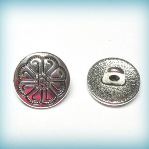 May include: Silver button with a floral design on the front and a shank on the back.