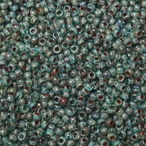 May include: A close-up image of a large quantity of small, round, turquoise glass beads with silver and red accents. The beads have a slightly iridescent finish.