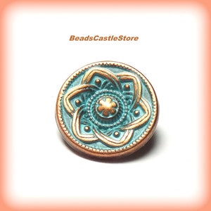 May include: A teal blue and copper button with a decorative, intricate design. The button features a central flower motif with a gold finish.