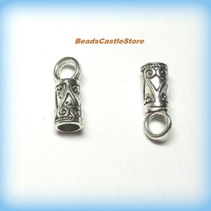 May include: Two silver metal end caps with a decorative design. Each cap has a small loop at the top.