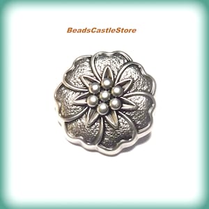 May include: Silver-toned metal flower charm with a textured surface and a raised center with five round accents. BeadsCastleStore is printed above the charm.