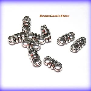 May include: Silver metal bead caps with a twisted design. The caps have a small hole for threading through cord or string.