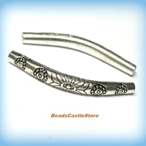 May include: Two silver metal bead caps with a curved shape and a floral design. The design features a repeating pattern of stylized flowers with a central circle.