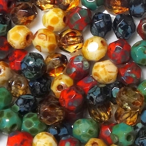 May include: Assortment of colorful glass beads with various patterns and textures. The beads are faceted and have a speckled or marbled appearance. Some beads are clear, while others are opaque. The beads are a mix of red, green, blue, brown, and white.