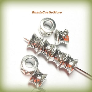 May include: Silver metal bead caps with a geometric design. The caps have a hole in the center for stringing. BeadsCastleStore is printed on the image.