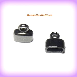 May include: Two black metal end caps with a loop at the top. The end caps are designed to be used on cords or straps.