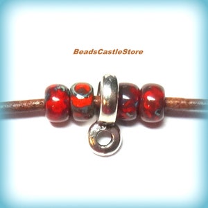 May include: Close-up of a leather cord with four red and black glass beads and a silver-colored metal clasp. The beads have a speckled design. The text "BeadsCastleStore" is in the upper center.