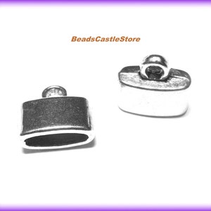 May include: Two silver metal end caps for jewelry making. The end caps are rectangular with a rounded top and bottom. One end cap has a loop on top for attaching a cord or chain.
