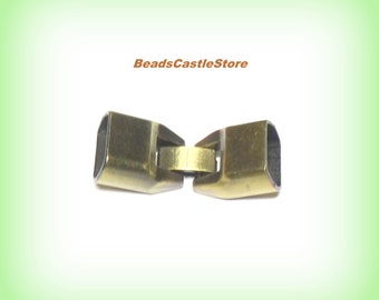 May include: A close-up of a gold-toned metal clasp for jewelry making. The clasp is made of two pieces that connect together.