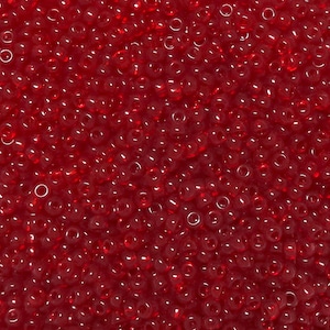 May include: A close-up image of a large quantity of small, round, red glass beads. The beads are translucent and have a slight shine.