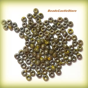 May include: A pile of approximately 100 small, round, gold and brown glass beads. The beads have a speckled, iridescent finish.