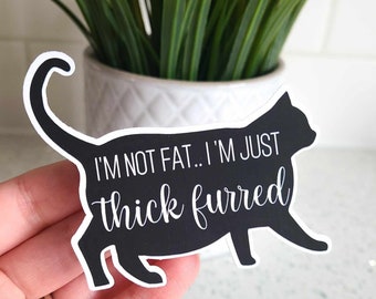 May include: Black and white sticker of a cat with the text "I'm not fat... I'm just thick furred".