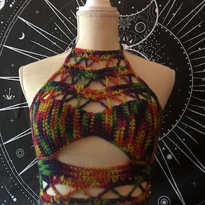 Könnte beinhalten: Ein mehrfarbiger Häkel-Halter-Top mit geometrischem Muster. Das Oberteil hat einen Ausschnitt an der Vorderseite und ist aus verschiedenen Farbtönen von Grün, Orange, Rot und Lila gefertigt.