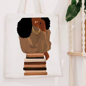 Puede incluir: Una bolsa de tela blanca con una ilustraci&oacute;n marr&oacute;n y negra de una mujer con el pelo negro rizado que lleva un jersey marr&oacute;n y joyas de oro. La mujer est&aacute; sentada sobre una pila de libros.