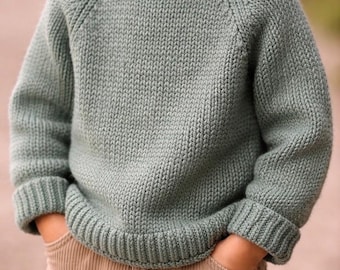 Può includere: Un maglione in maglia a maniche lunghe color verde salvia con girocollo a coste, polsini a coste e orlo a coste, abbinato a pantaloni in velluto a coste color marrone chiaro. Il maglione presenta un classico punto rasato e maniche raglan.