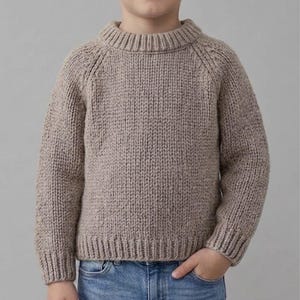 Puede incluir: Un suéter de punto grueso de manga larga en color beige neutro. La prenda presenta un cuello redondo acanalado grueso, puños acanalados y un dobladillo acanalado. El patrón de tejido es consistente en todo el cuerpo y las mangas, mostrando una textura de hilo grueso.