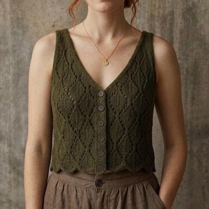 May include: An olive green sleeveless knit vest featuring a V-neckline, a front button closure with six matching buttons, and a detailed leaf-like openwork pattern throughout the fabric. The garment has a scalloped hemline and a fitted silhouette.